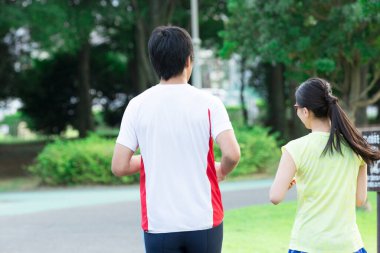 Sportif genç Asyalı çift parkta koşuyor.