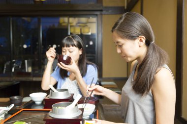 Güzel Asyalı kadınlar restoranda geleneksel Japon yemekleri yiyorlar.