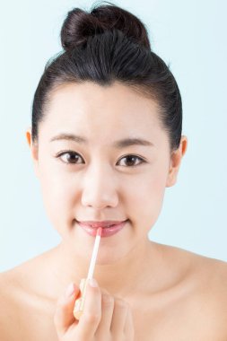 Genç, güzel Asyalı kadın dudak parlatıcısı sürüyor.