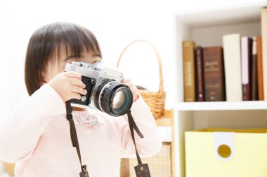 Evde eski model fotoğraf makinesi olan küçük bir kız. 