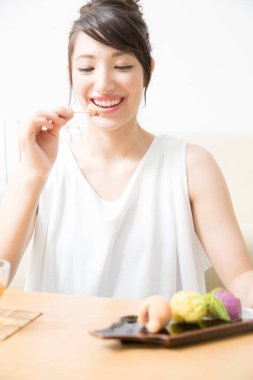 Evde pasta yiyen Asyalı kadın. 