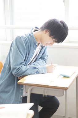 Genç adam bir deftere yazıyor.