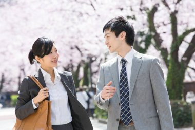 Şehir caddesinde kiraz çiçekleri olan iki Japon iş adamı.
