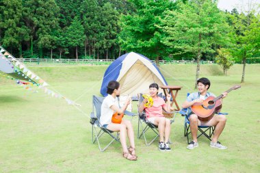 Mutlu Asyalı arkadaşlar kamp parkında müzik aletleri çalıyorlar.