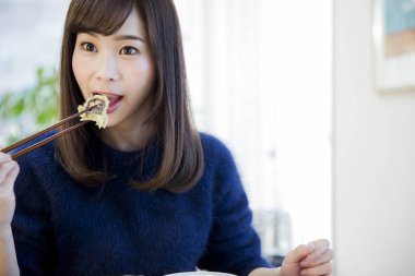 Lokantada yemek çubuklarıyla yemek yiyen kadın.