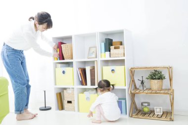 Çocuk yakınlarda oynarken, kadın raf düzenliyor