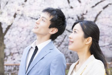 Parkta çiçek açan sakura ağaçları olan genç Asyalı çift.