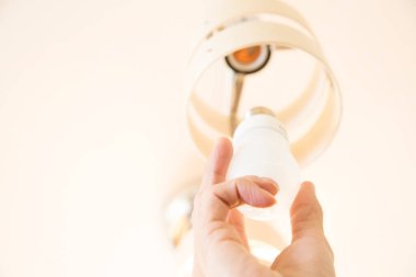 Avizedeki ampulü değiştiren elektrikçinin eli. 