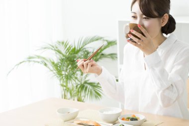 Genç Japon kadın çubuklarla yemek yiyor.