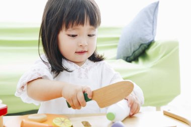 Evdeki oturma odasında oynayan tatlı Asyalı küçük kız.