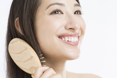 Güzel Japon kadın saçını tarıyor beyaz arka planda.