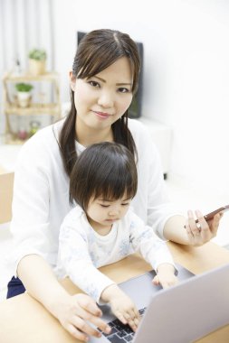 Anne ve kızı evde dizüstü bilgisayar kullanıyorlar.