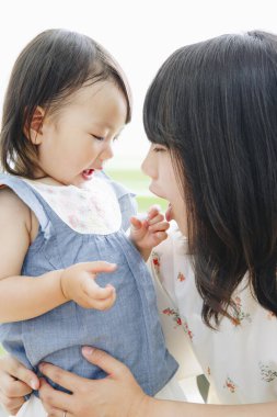 Asyalı anne kızını kucağında tutuyor ve evde eğleniyor. 