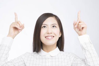 İşaret parmaklarıyla beyaz arka planda el kol hareketi yapan güzel bir Japon kadının stüdyo fotoğrafı. 