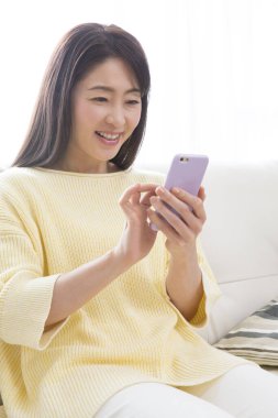 Evde cep telefonu kullanan bir kadın 