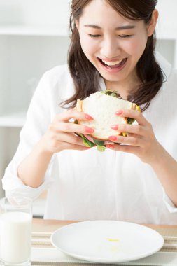 Genç Asyalı kadın lezzetli sandviçler yiyor.