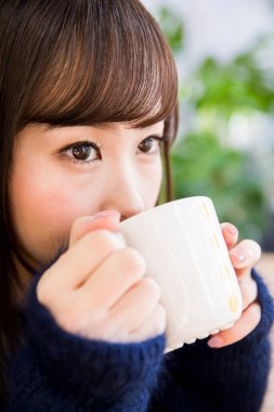 Kafede kahve içen genç Asyalı kadın.