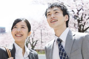 Şehir caddesinde kiraz çiçekleri olan iki Japon iş adamı.