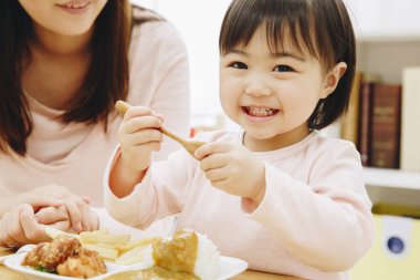 Annesi evde Japon yemeği yiyen tatlı Asyalı kız.