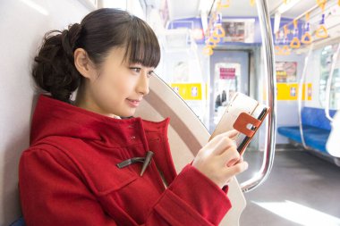  Kasık taşımacılığında akıllı telefonu olan Japon kadın. 