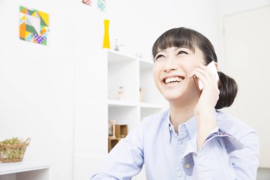 Genç Asyalı kadın cep telefonuyla konuşuyor.