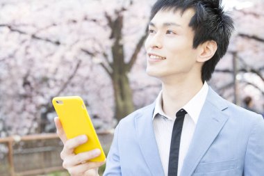 Parkta akıllı telefon kullanan iş adamı 