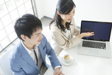 Genç Japon iş adamları ofiste dizüstü bilgisayarla çalışıyorlar.