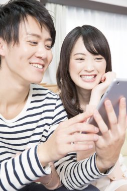 Mutlu Asyalı çift evde tablet kullanıyor.