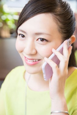 Kafede akıllı telefon kullanan Asyalı kadın.