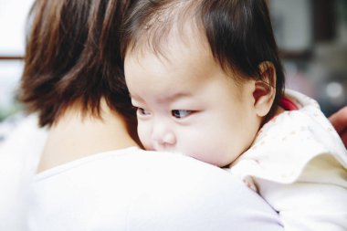 Bebek evin içinde kadının omzunda dinleniyor.