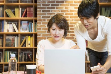 Ofiste bilgisayarla çalışan Asyalı genç kadın ve erkek.