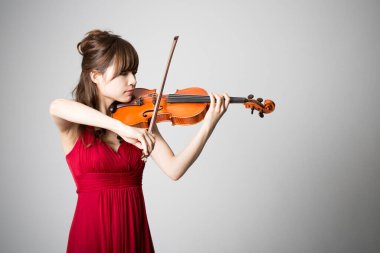 Genç, güzel Asyalı kadın keman çalıyor.