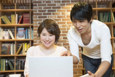 Ofiste bilgisayarla çalışan Asyalı genç kadın ve erkek.