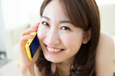 gülümseyen genç Asyalı kadın akıllı telefon kullanıyor.