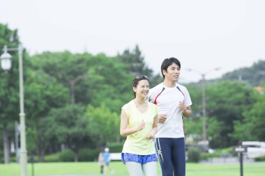 Sportif genç Asyalı çift parkta koşuyor.