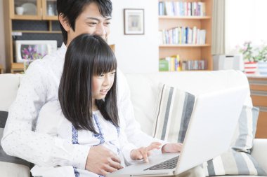 Evde dizüstü bilgisayar kullanan mutlu bir Asyalı aile.