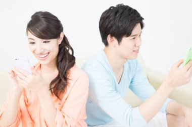 Kanepede akıllı telefonları olan genç çift.