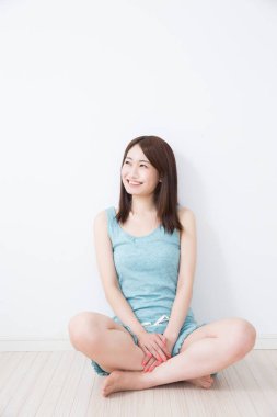 Gülümseyen Asyalı kadın evde yerde oturuyor.