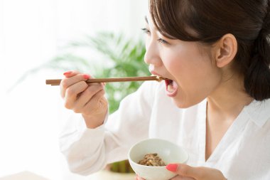 Asyalı kadın kahvaltısını çubuklarla yer.