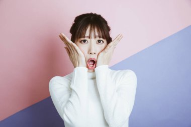 Pembe mavi arka planda şaşkın bakışlı genç kadınlar.