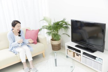 Evdeki kanepede gülen kadın. 