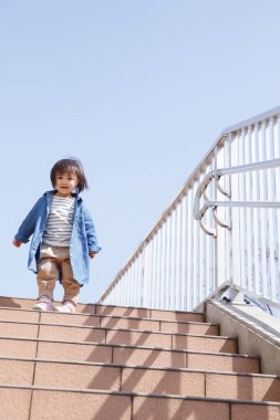 Genç Asyalı çocuk merdivenleri tırmanıyor.