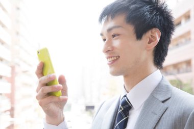 Genç işadamı şehirde akıllı telefon kullanıyor. 