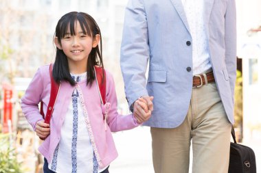 Asyalı baba ve kızı sokakta birlikte yürüyorlar.