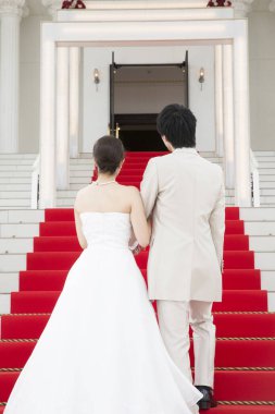 Merdivenlerde kırmızı halıyla yürüyen genç ve güzel bir çiftin arka manzarası. 