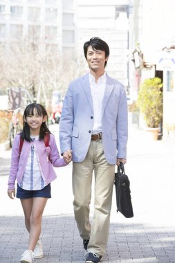 Asyalı baba ve kızı sokakta birlikte yürüyorlar.