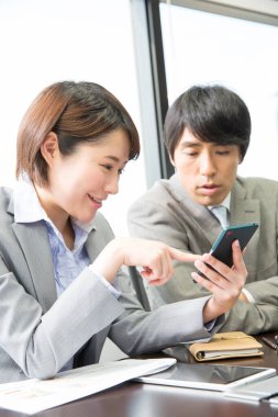 Ofisinde akıllı telefonu olan bir iş kadını.