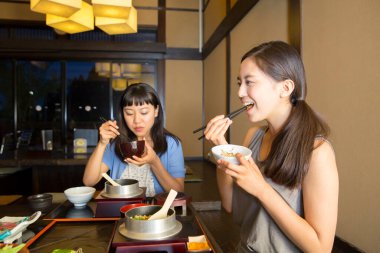 Güzel Asyalı kadınlar restoranda geleneksel Japon yemekleri yiyorlar.