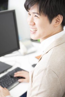 Genç Asyalı adam ofiste çalışıyor.