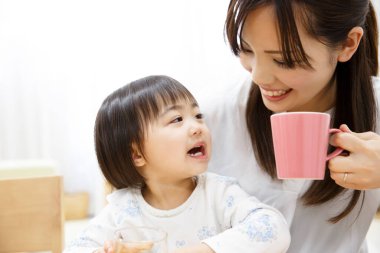 Asyalı anne ve küçük kız kahvaltı yapıyorlar. 